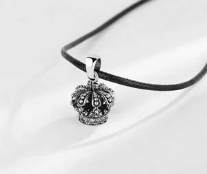 Vue macro d'un pendentif couronne en argent vieilli serti de zircons sur cordon noir