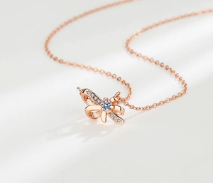 Détail macro du collier nœud en or rose avec zircon brillant et chaîne délicate