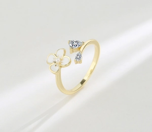 Detail of adjustable gold ring featuring a white flower, pearl, and zircon stones
