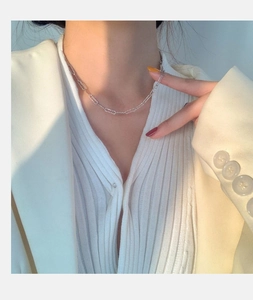 Detail of S925 sterling silver paperclip chain necklace on a model wearing a white suit