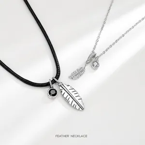 Detail of silver feather couple necklaces with black leather cord and metal chain links