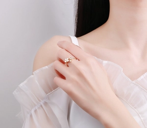 Detail of adjustable gold ring with white clover charm and teardrop zircon on finger