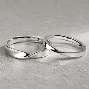 Close-up of silver Mobius couple rings featuring a minimalist twisted metal design