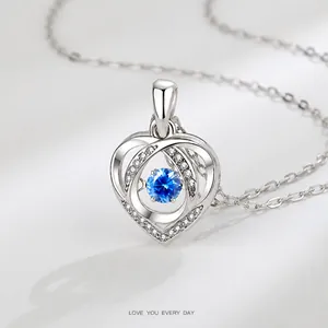 Macro detail of silver heart pendant with blue gemstone and shimmering micro-set crystals