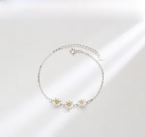 Macro detail of S925 sterling silver daisy bracelet with gold centers and heart tag
