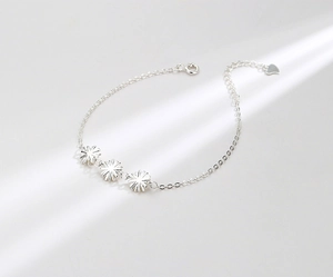 Detail of S925 sterling silver daisy bracelet with floral charms and heart pendant