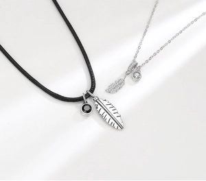 Detailed close-up of sterling silver feather pendants with black and white gemstones