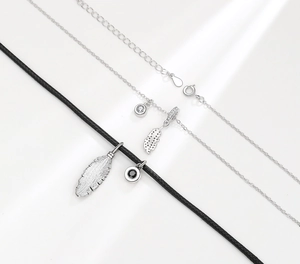 Detail of silver feather pendants on black braided cord and elegant silver link chains