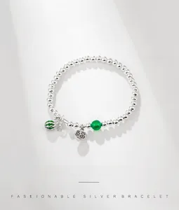 Macro detail of S925 sterling silver beaded bracelet with Fu character and green enamel pendant