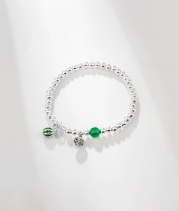 Detailed macro shot of S925 silver beaded bracelet with Fu charm and green enamel charm