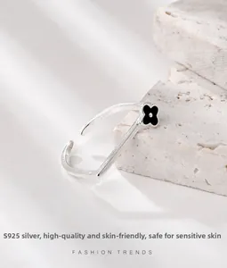 Detail of S925 sterling silver square open ring with a black clover on white stone stand