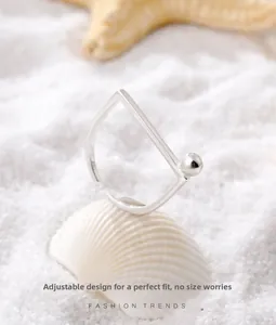 Close-up of adjustable S925 sterling silver ring with metal beads on beach sand