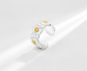 Macro detail of three daisy flowers with golden centers on a s925 silver open ring band