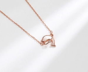 Gros plan du collier pendentif dauphin en or rose avec incrustation de nacre blanche