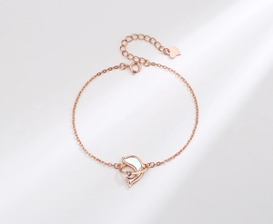 Detail of rose gold dolphin bracelet with white mother-of-pearl and small zircon stone