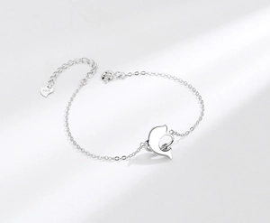 Macro shot of S925 sterling silver dolphin charm bracelet with adjustable heart clasp