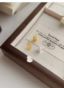 Detailed close-up of gold and silver gourd earrings with textured finish on jewelry tray