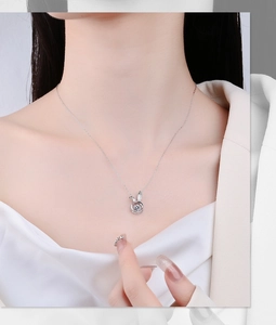 Detail of S925 silver dancing rabbit necklace with a shimmering crystal pendant on model
