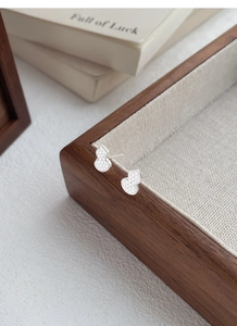 Macro detail of S999 sterling silver gourd stud earrings with hammered texture on wood tray