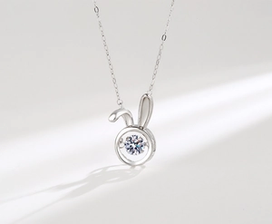 Macro shot of silver bunny pendant featuring a dancing center stone and O-chain details