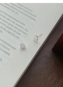 Detail view of S999 silver gourd earrings with geometric texture on a vintage book base