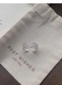 Détail d'une bague multicouche en argent S925 sur une pochette cadeau crème