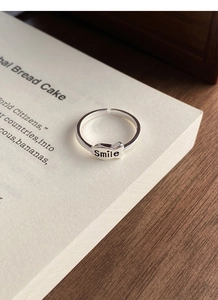 Detail of S925 sterling silver fish ring with Smile engraving on white book page