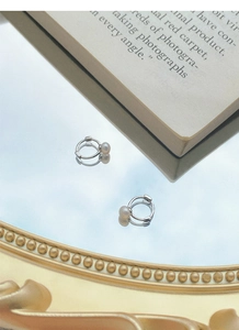 Gros plan de boucles d'oreilles créoles en argent S925 et perles sur un miroir rétro