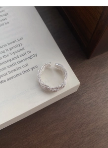 Détail macro d'une bague tressée en argent S925 sur les pages d'un livre vintage
