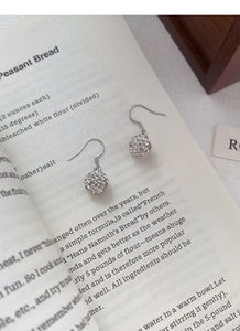 Detail shot of silver drop earrings with crystal spheres on a minimalist book background