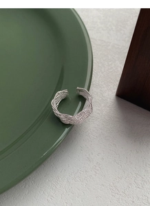 Vue macro d'une bague en argent tressée multicouche sur une assiette vert foncé