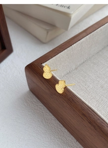 Detailed close-up of golden gourd stud earrings with intricate honeycomb texture