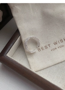 Détail d'une bague multicouche en argent S925 tressé sur une pochette cadeau chic