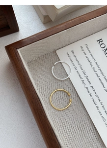 Detailed view of adjustable twisted rope rings in gold and silver on a linen tray