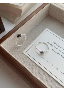Detail of S925 silver adjustable rings with black flower and twisted rope band texture