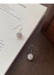 Macro shot of sparkling crystal paved sphere earrings with silver-tone fish hook wires