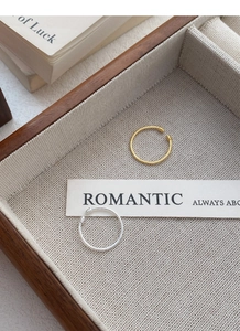 Detail of twisted S925 sterling silver open rings in gold and silver finishes on a wooden tray