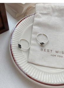 Detailed close-up of S925 silver rings with black enamel flower and twisted band design