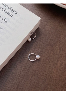 Détail de boucles d'oreilles créoles en argent S925 et perles sur fond de bois sombre