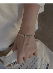 Détail d'un ensemble bracelet à perles argentées et bague torsadée sur un poignet