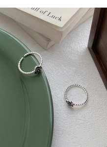Detailed shot of S925 silver twist rings featuring black enamel flowers on a green plate