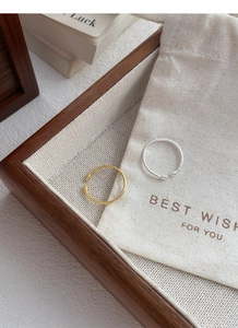 Detail view of twisted rope design rings in silver and gold on a rustic wooden tray