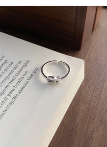 Detail shot of S925 silver adjustable ring featuring a Smile engraved oval metal plate