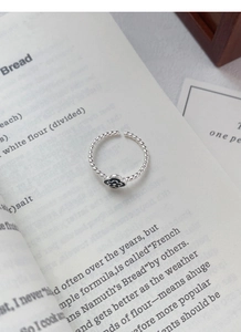Detailed shot of silver flower ring with black enamel on an open book page