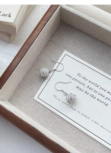 Macro view of S925 sterling silver ball earrings with sparkling pavé crystals and hooks