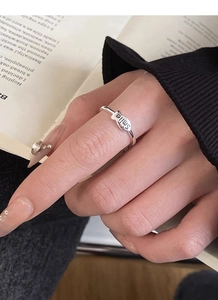 Close-up of S925 sterling silver smile letter ring worn on a finger over a book