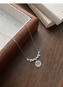 Macro detail of S925 silver necklace with sparkling zircon pendant and moonstone charm