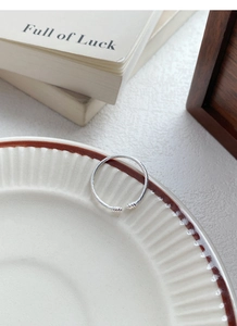 Top view of a minimalist S925 sterling silver twisted rope open ring on a ceramic plate
