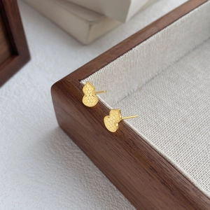 Exquisite gold gourd-shaped stud earrings with honeycomb texture on a wooden tray