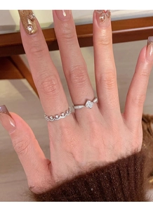 Gros plan d'une bague couronne en argent S925 et d'une bague diamant carré portées ensemble